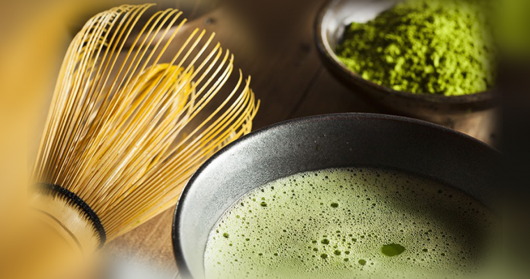 Bamboo whisk beside a prepared bowl of matcha